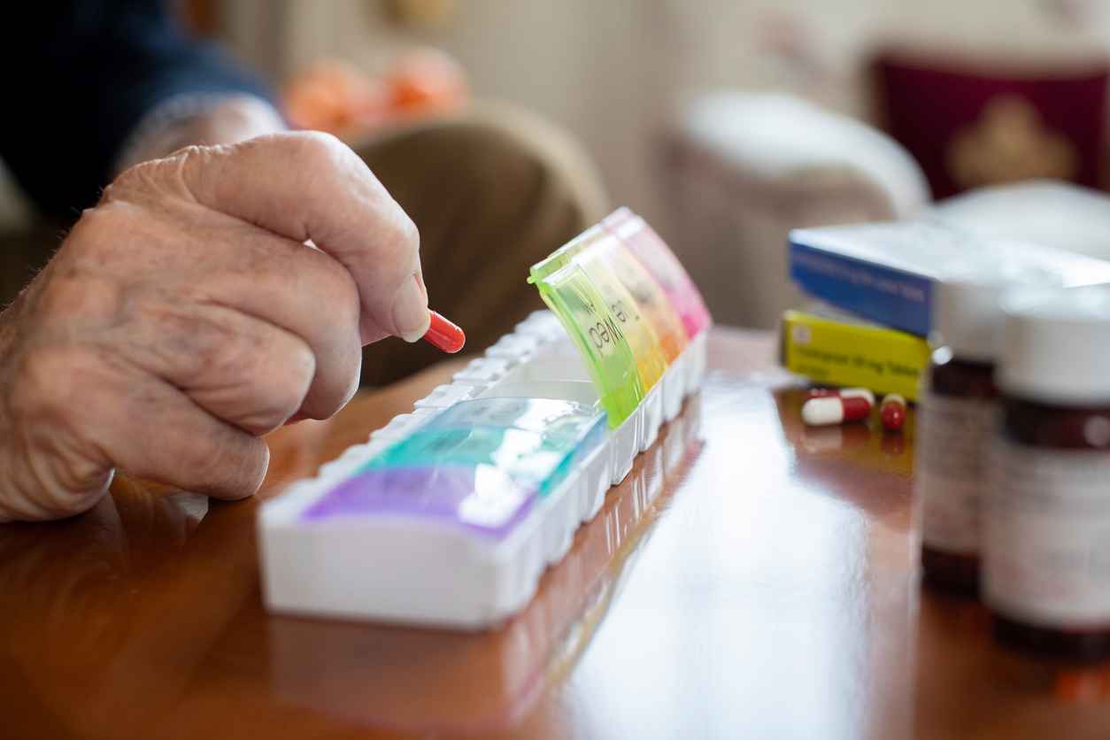 Close Up Of Senior Man Organizing Medication Into Pill Dispenser; Tips for Managing Medications at Home