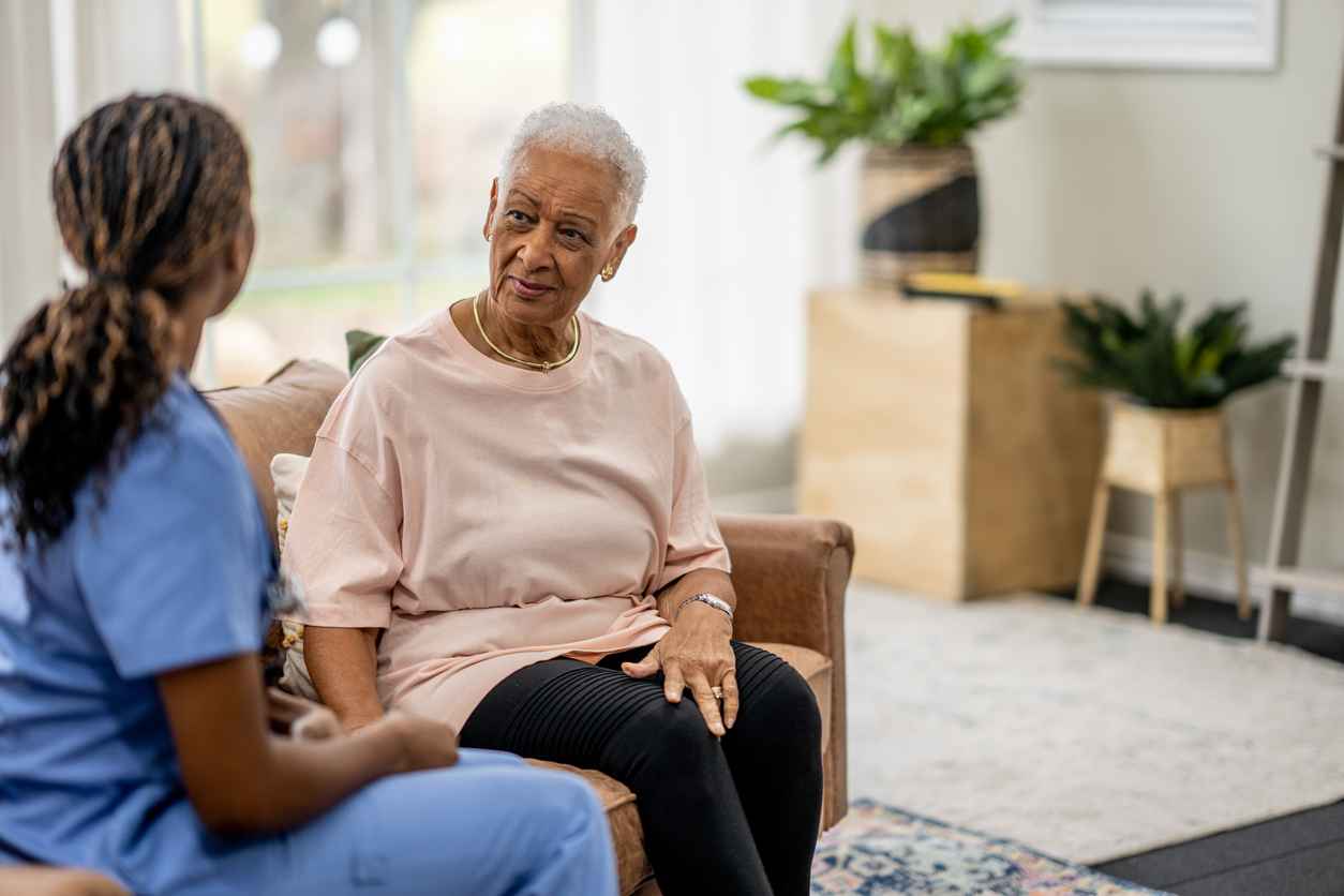 A senior sits with a Home Care nurse in the comfort of her own home as they meet to discuss her health concerns.
