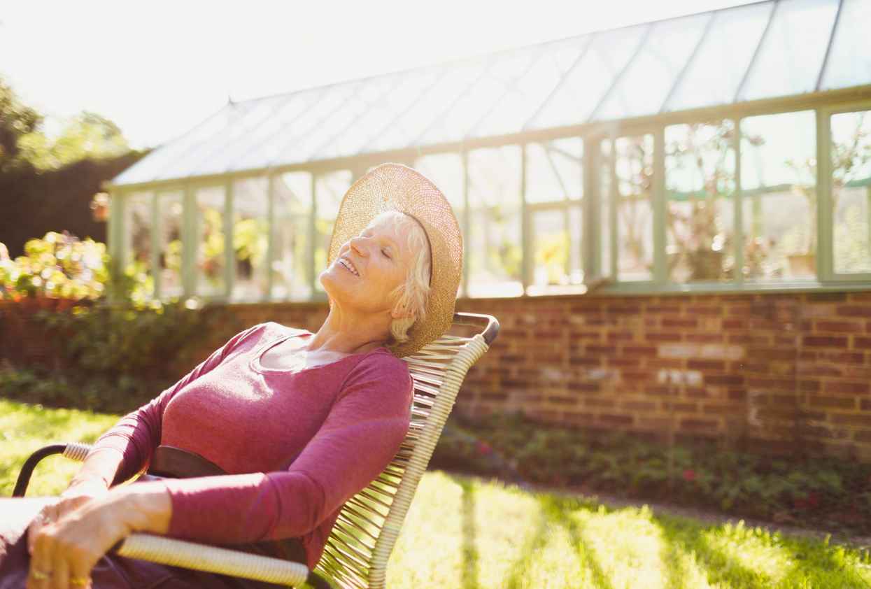 Carefree senior woman relaxing outside sunny greenhouse